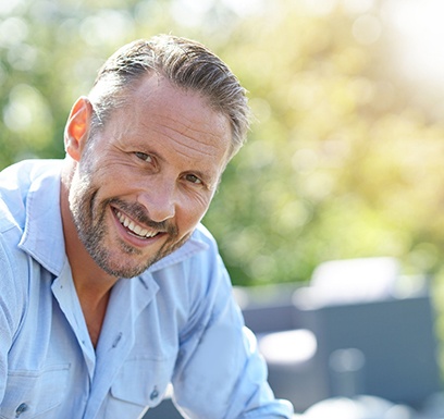 a man smiling and sitting outside