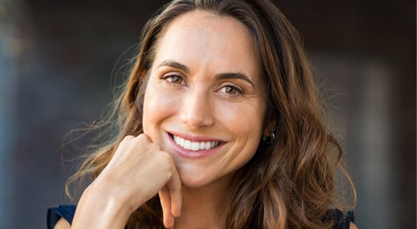 a woman smiling after receiving dental implants