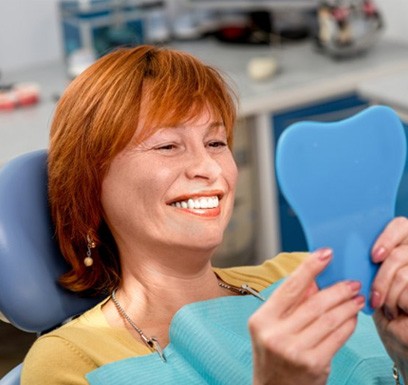 a dental patient checking her teeth with a mirror
