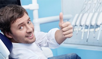 Man sitting in dental chair giving thumbs up