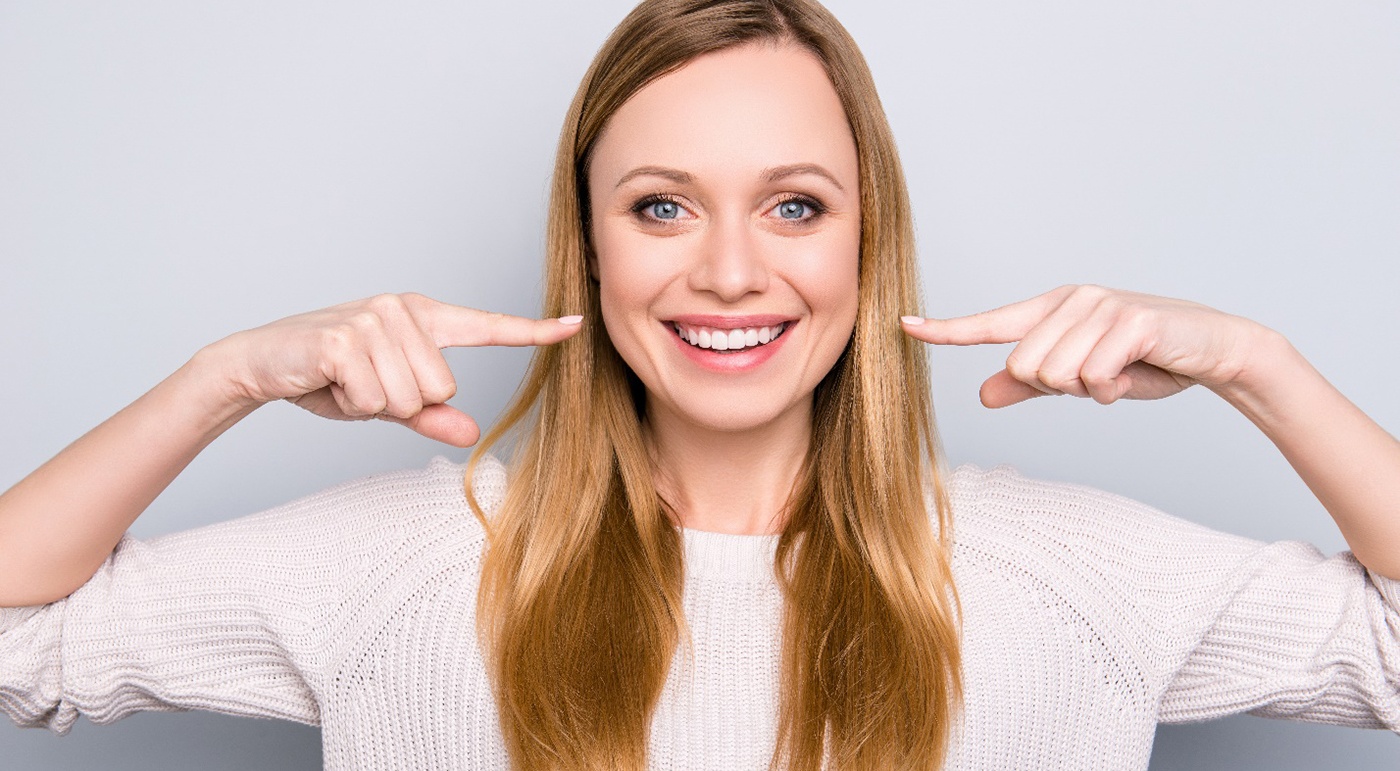 woman smiling and pointing to her teeth 