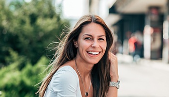Woman with long hair sitting outside and smiling