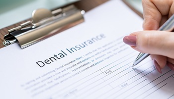 Filling out dental insurance form on a clipboard