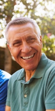 Older man in green polo shirt laughing outdoors