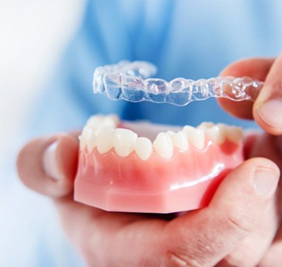 Dentist holding mouth mold and Invisalign® in Tulsa  