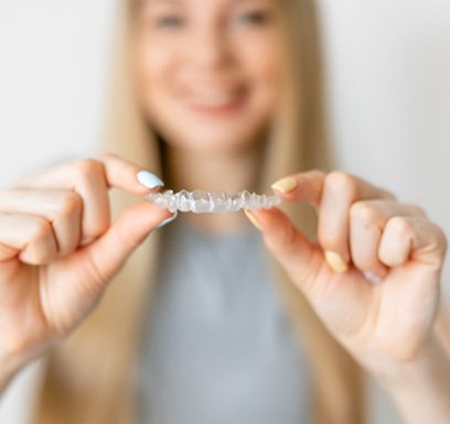 Girl holding Invisalign® aligner in Tulsa  