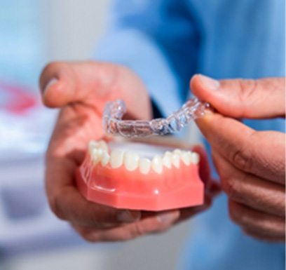 Tulsa dentist placing Invisalign over model of teeth