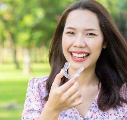 Smiling woman placing an Invisalign aligner