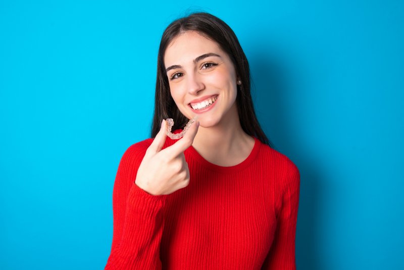 Young woman holding her Invisalign aligner