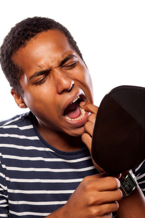 Man with loose tooth looking in handheld mirror